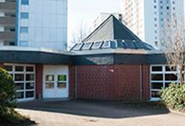 Außenansicht eines modernen Backsteingebäudes mit markantem Zeltdach.